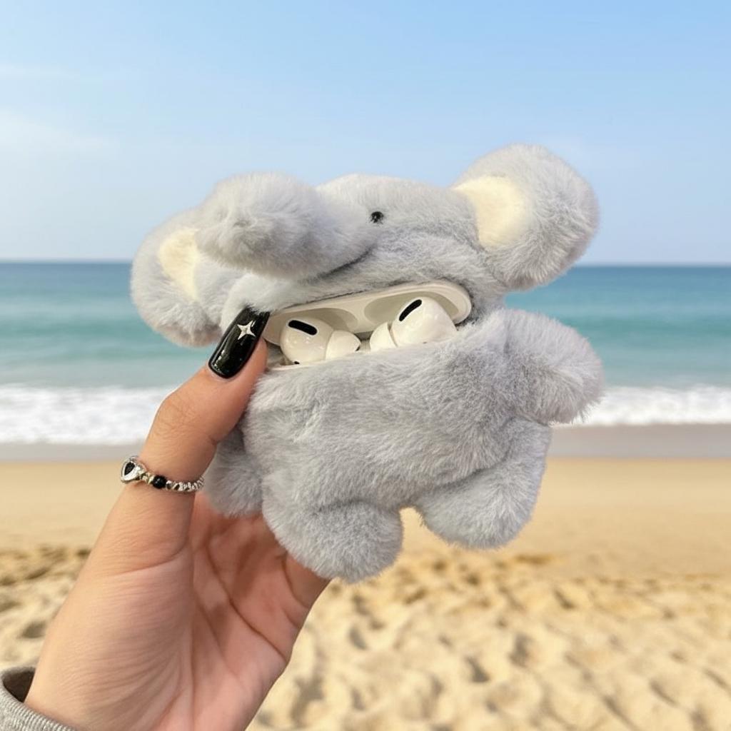 Gray elephant-shaped airpod case held by a hand on a beach.