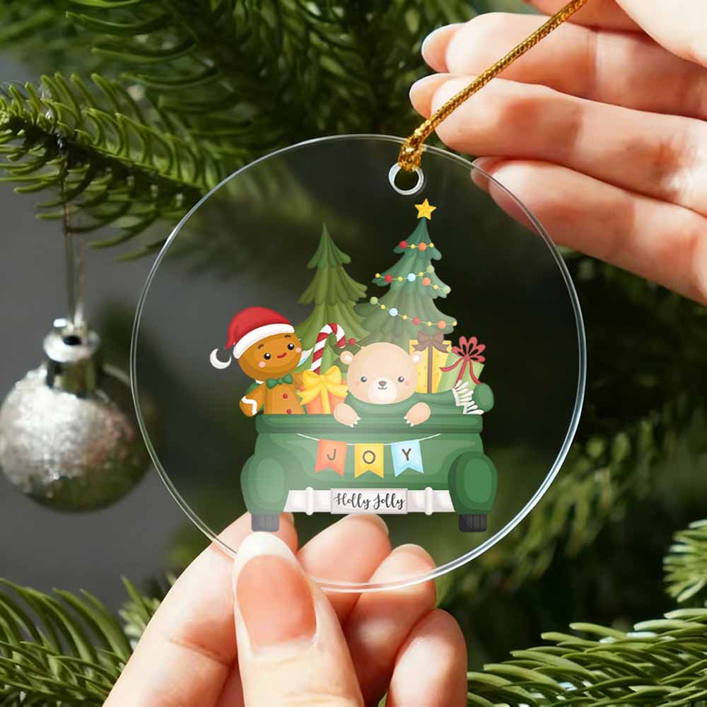 Clear Christmas ornament with cartoon characters and festive text, held by hands against a tree background.