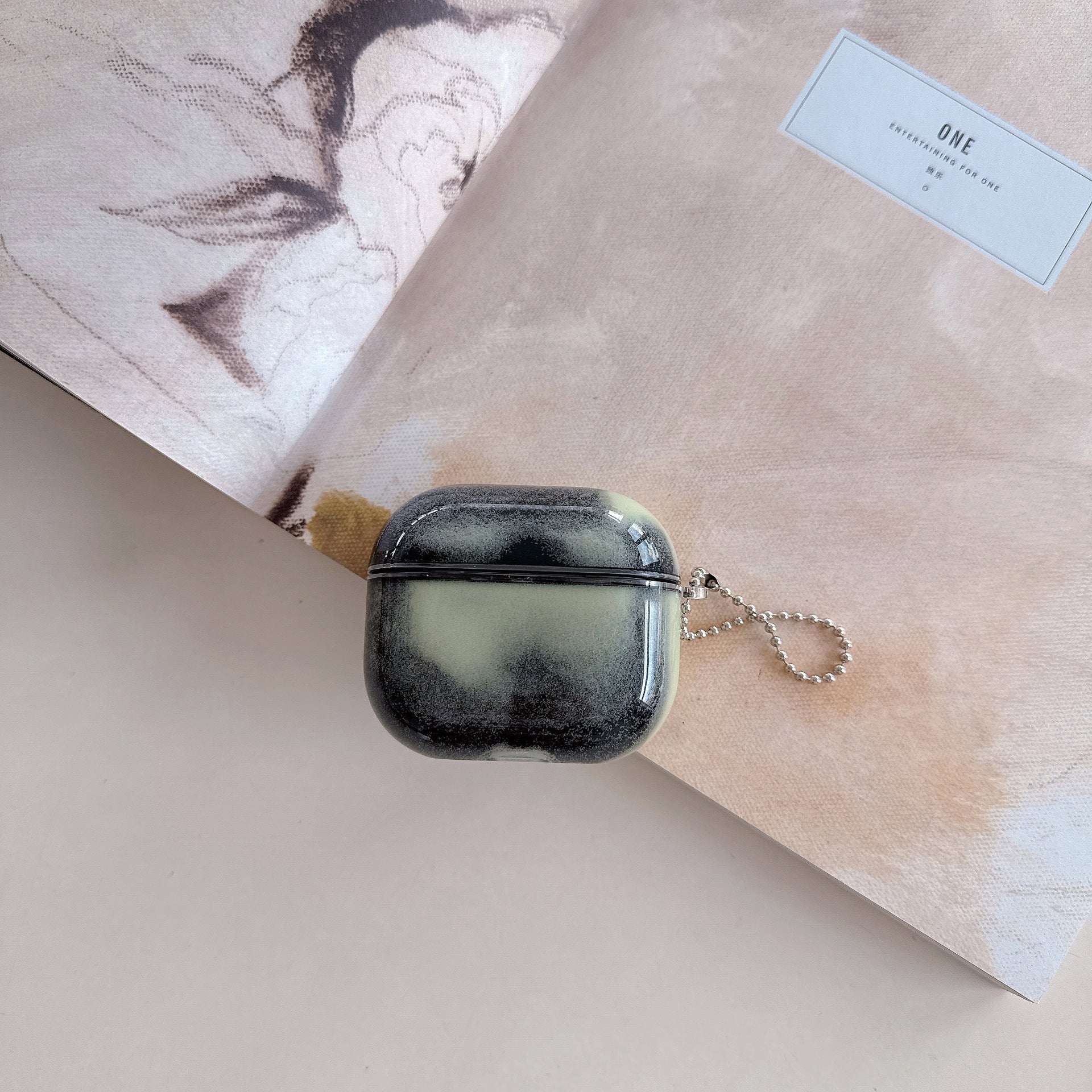 Black airpod case with a keychain on a light surface with a blurred background