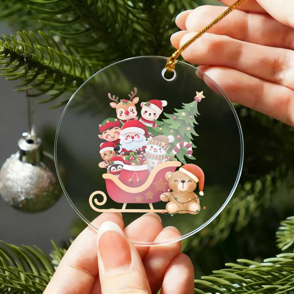 Clear Christmas ornament with Santa Claus and reindeer design held by a hand against a green tree background.