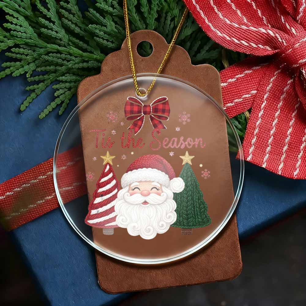 Christmas ornament with Santa Claus design on a brown tag, surrounded by greenery and ribbons.